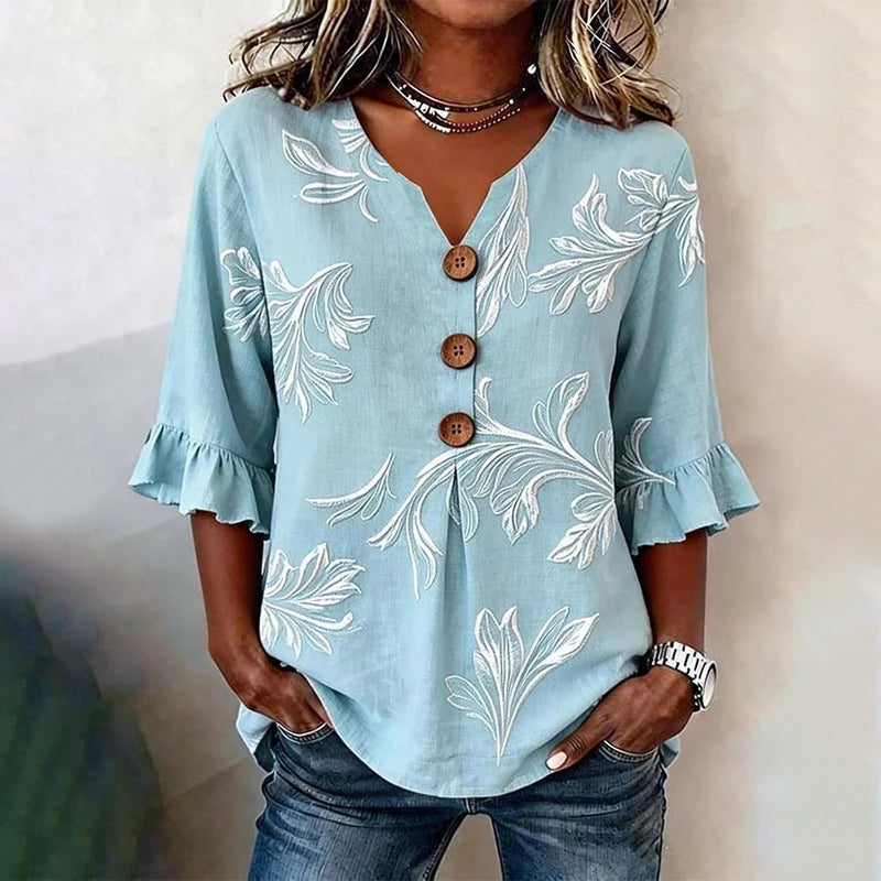 Woman in striped top, heart necklace, white pants.