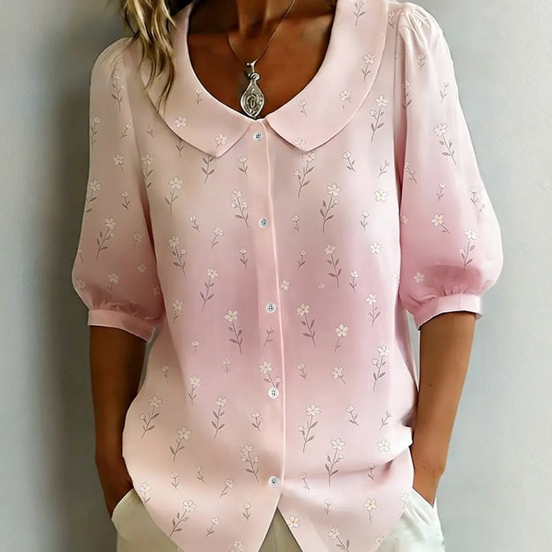 Woman in striped top, heart necklace, white pants.